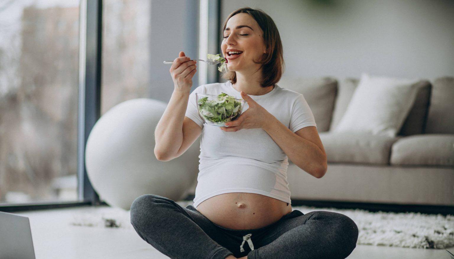 young-pregnant-woman-eating-salad-home