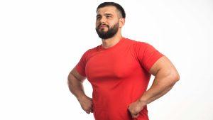 sportive-man-red-shirt-demonstrating-his-arm-muscles-looks-confident (1)