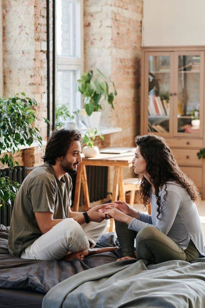 a couple sitting on the bed while having conversation