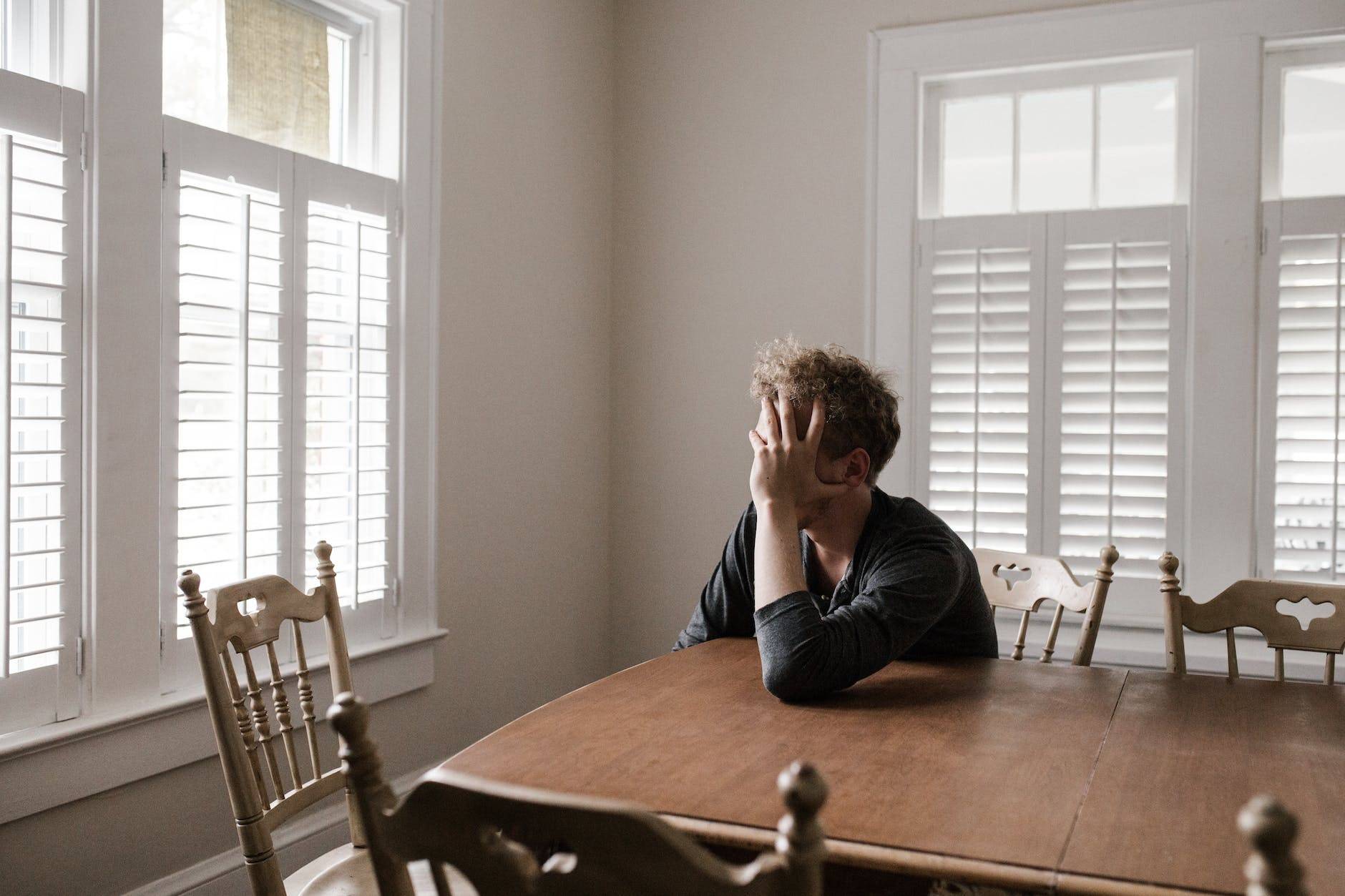 photo of man leaning on wooden table