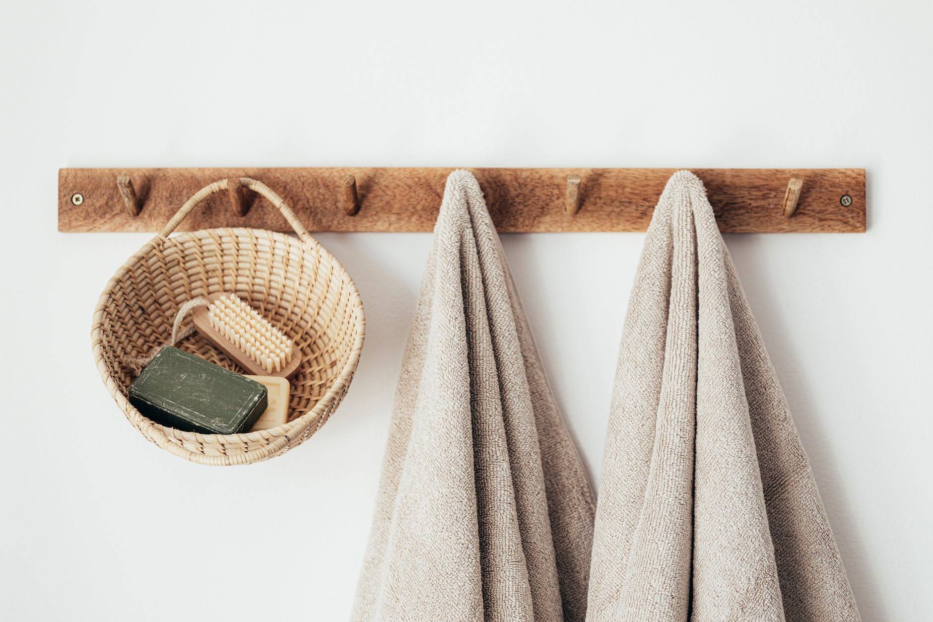 wooden hanger with towels and basket with bathroom products