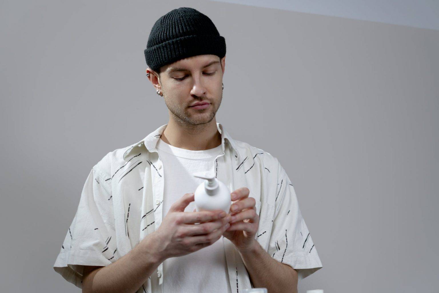 photo of a man with a black beanie holding a shampoo bottle