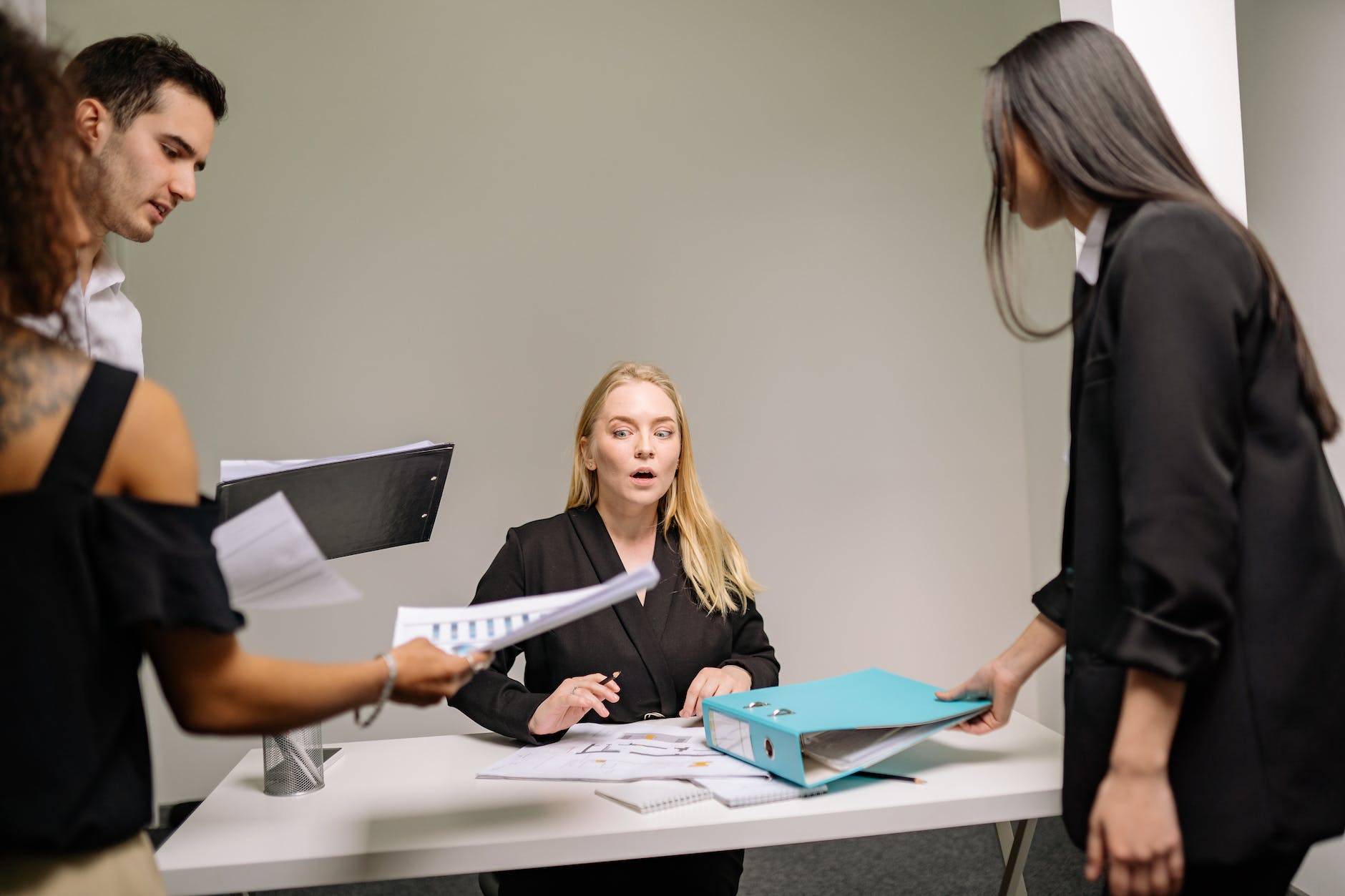 a woman in black blazer sitting at the desk with documents