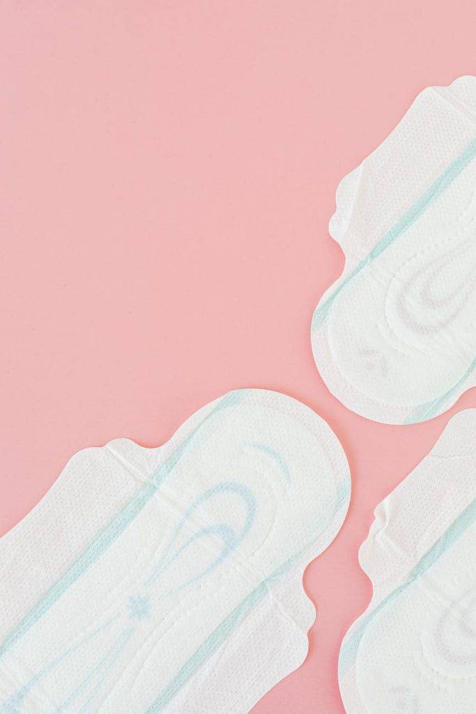 white and blue sanitary napkins on pink surface