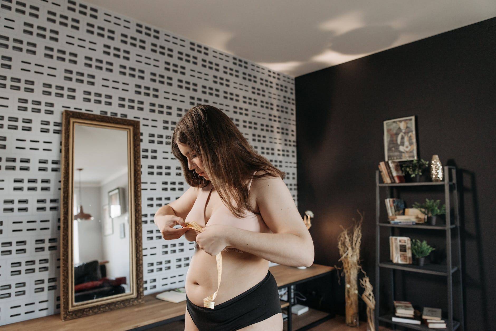 woman in brown brassier and black panty holding a measuring tape