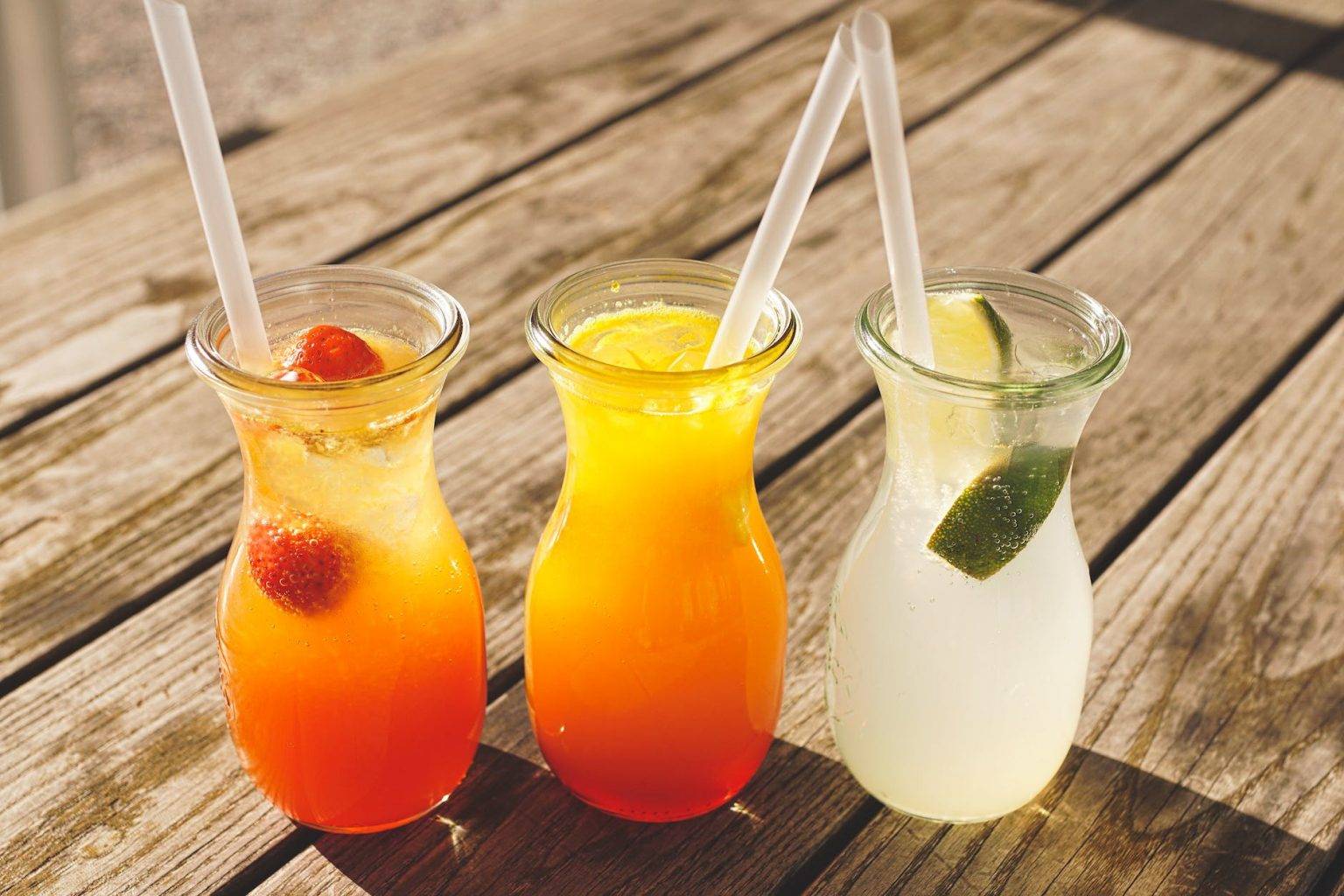 three assorted fruit juice in glasses