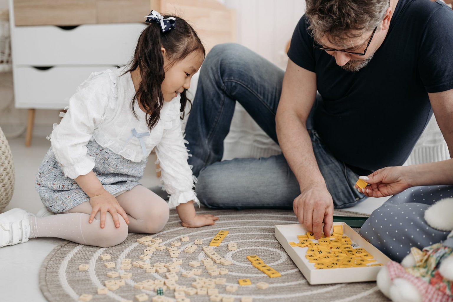 father and daughter sitting on the floor and playing a game